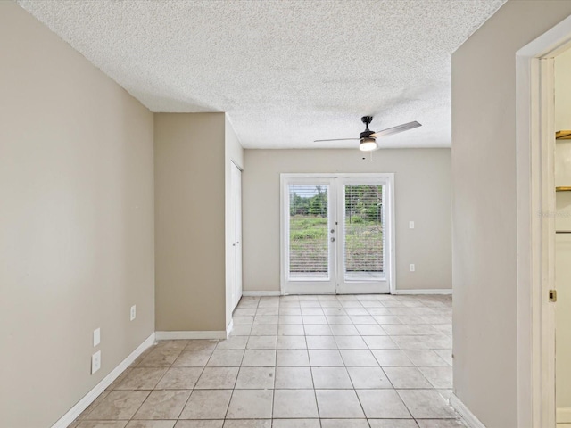 spare room featuring light tile patterned floors, baseboards, ceiling fan, a textured ceiling, and french doors