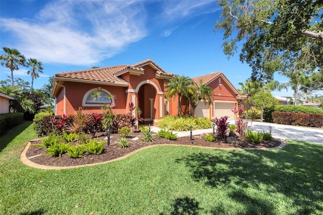mediterranean / spanish-style house with a tiled roof, stucco siding, a front yard, a garage, and driveway