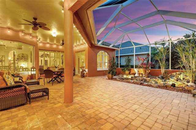 view of patio featuring outdoor dining space, ceiling fan, and glass enclosure