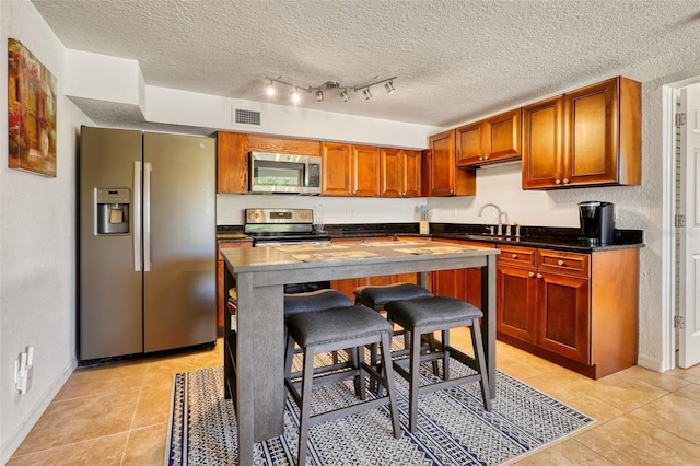 2605 Sunnybrook Dr, Sarasota, FL 34239 - kitchen with visible vents, appliances with stainless steel finishes, light tile patterned floors, and dark countertops