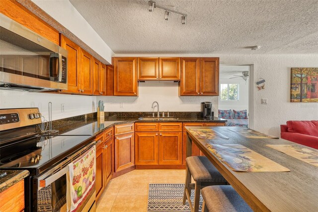 2605 Sunnybrook Dr, Sarasota, FL 34239 - kitchen featuring a sink, a textured ceiling, appliances with stainless steel finishes, and brown cabinets