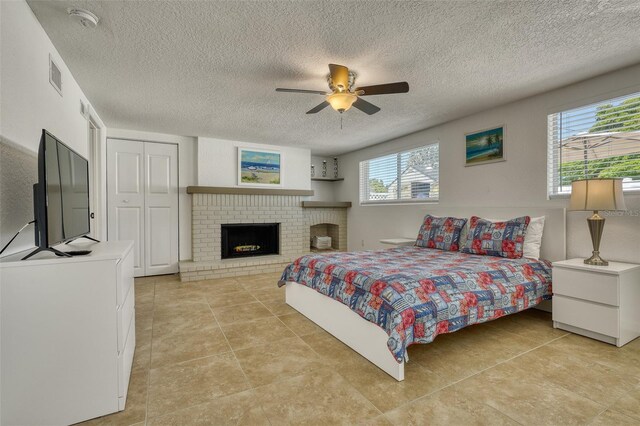 2605 Sunnybrook Dr, Sarasota, FL 34239 - bedroom featuring visible vents, a brick fireplace, ceiling fan, a textured ceiling, and light tile patterned floors