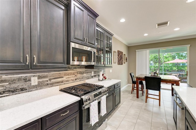 kitchen with light countertops, visible vents, crown molding, tasteful backsplash, and appliances with stainless steel finishes