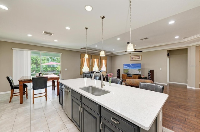kitchen with light countertops, visible vents, ornamental molding, a sink, and stainless steel dishwasher