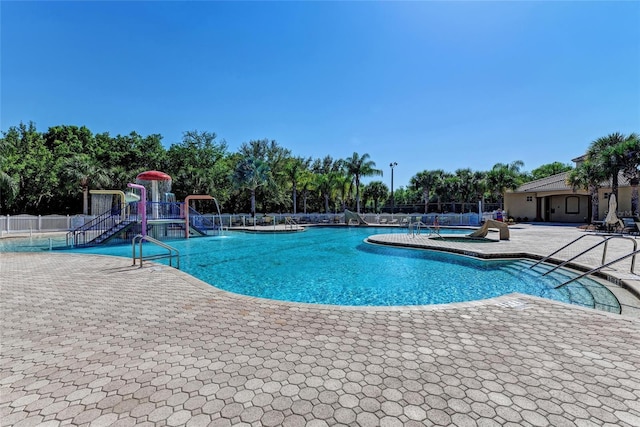 pool featuring fence, playground community, and a patio area