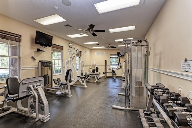 gym featuring a wealth of natural light, visible vents, ceiling fan, and a textured ceiling
