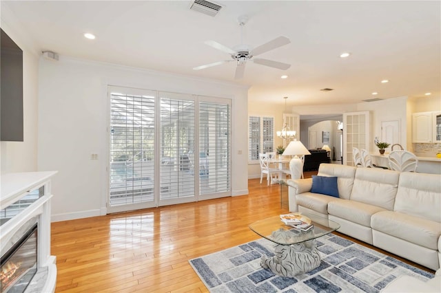 1860 Citron St, Punta Gorda, FL 33980 - living room featuring visible vents, baseboards, light wood-type flooring, ceiling fan with notable chandelier, and a glass covered fireplace