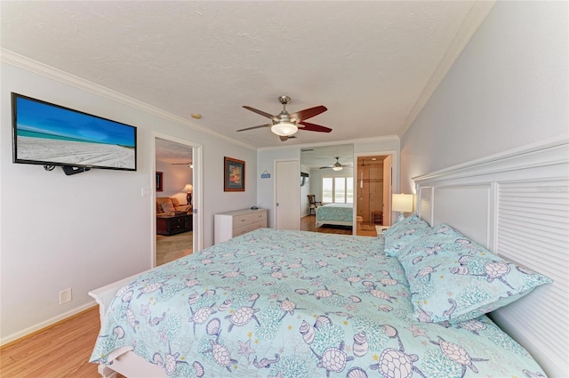 bedroom featuring ornamental molding, a textured ceiling, ceiling fan, and wood finished floors