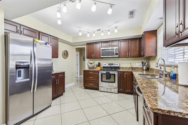 kitchen featuring light tile patterned floors, stainless steel appliances, dark stone countertops, a sink, and visible vents