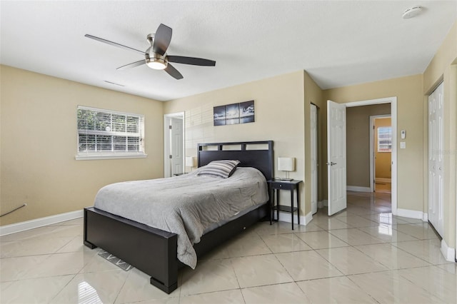 bedroom with baseboards, visible vents, a ceiling fan, and light tile patterned floors