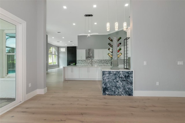 600 Eagle Watch Ln, Osprey, FL 34229 - kitchen featuring light wood-type flooring, white cabinets, wall chimney range hood, tasteful backsplash, and pendant lighting