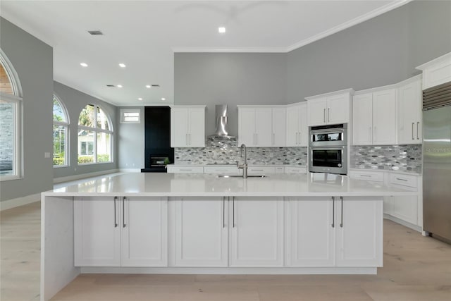 600 Eagle Watch Ln, Osprey, FL 34229 - kitchen with wall chimney exhaust hood, appliances with stainless steel finishes, decorative backsplash, white cabinets, and ornamental molding