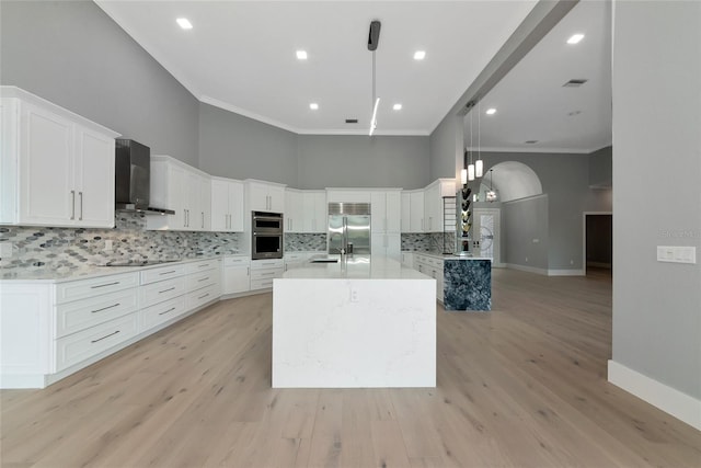 600 Eagle Watch Ln, Osprey, FL 34229 - kitchen with wall chimney exhaust hood, appliances with stainless steel finishes, crown molding, light countertops, and a center island with sink