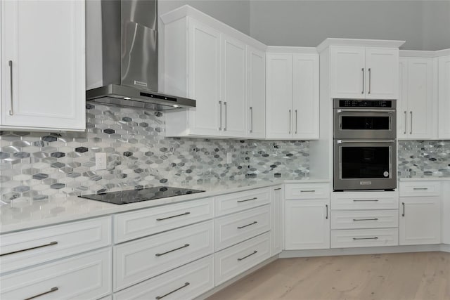600 Eagle Watch Ln, Osprey, FL 34229 - kitchen with wall chimney range hood, stainless steel double oven, light countertops, and black electric cooktop