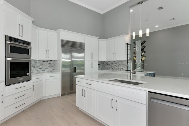 600 Eagle Watch Ln, Osprey, FL 34229 - kitchen with stainless steel appliances, ornamental molding, decorative backsplash, light countertops, and light wood-style flooring