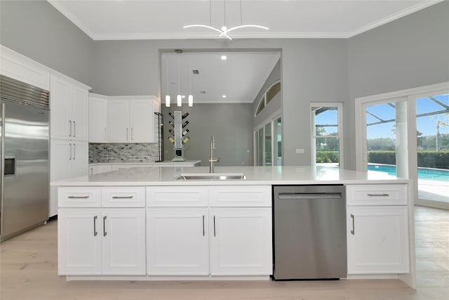 600 Eagle Watch Ln, Osprey, FL 34229 - kitchen featuring stainless steel appliances, white cabinets, decorative backsplash, light countertops, and crown molding