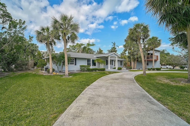 ranch-style home featuring a front lawn, curved driveway, and covered porch