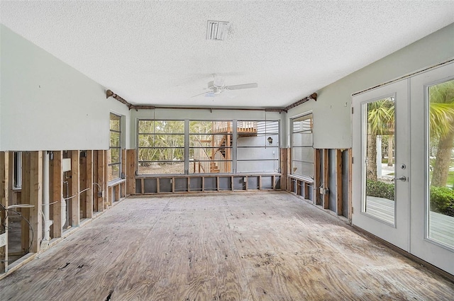unfurnished sunroom featuring ceiling fan, a textured ceiling, and french doors