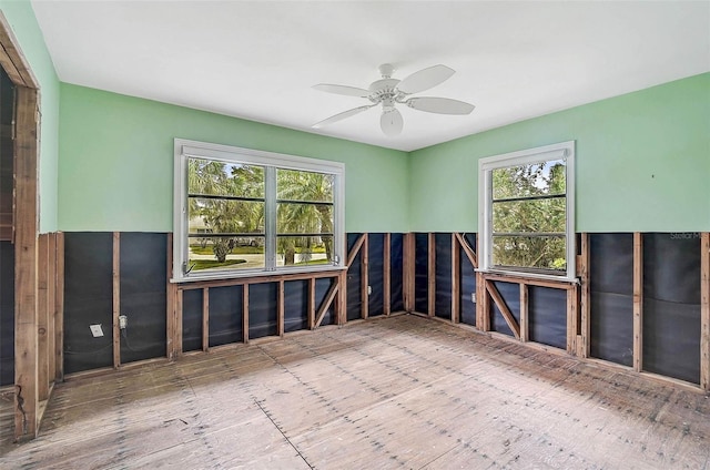 unfurnished room featuring healthy amount of natural light, ceiling fan, and hardwood / wood-style floors