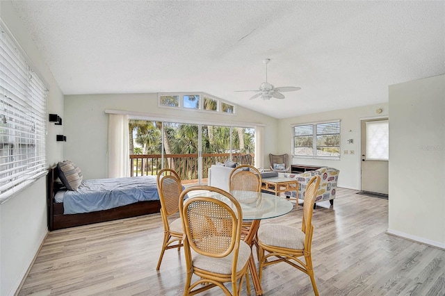 dining area featuring ceiling fan, a textured ceiling, lofted ceiling, light wood finished floors, and baseboards