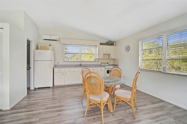 dining space with lofted ceiling, a wall mounted AC, light wood-style floors, baseboards, and a textured ceiling