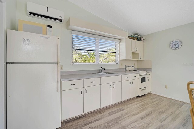 kitchen featuring white appliances, a sink, a wall unit AC, light countertops, and light wood-style flooring