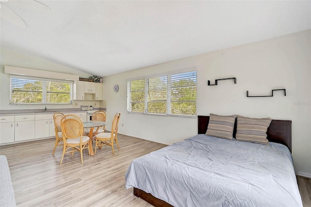 bedroom featuring light wood-style flooring, lofted ceiling, and a sink