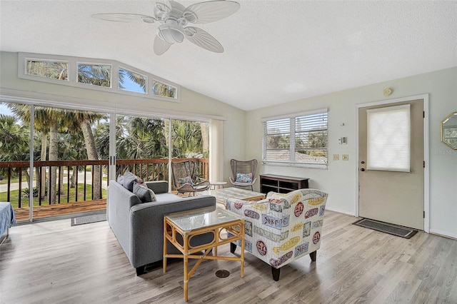 living area featuring light wood-style floors, ceiling fan, vaulted ceiling, and a textured ceiling