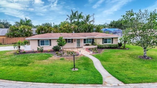ranch-style house featuring stucco siding, fence, and a front lawn