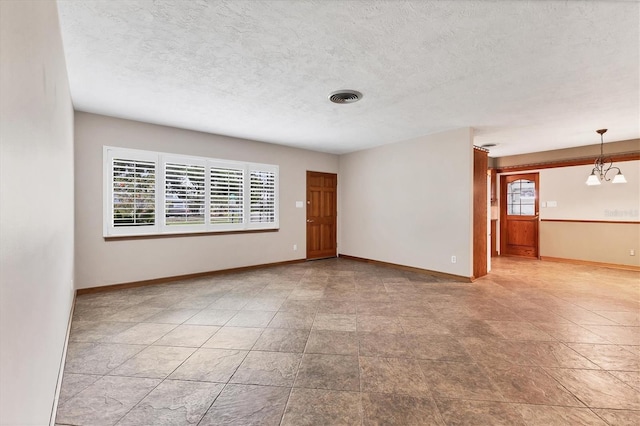 unfurnished room with a notable chandelier, visible vents, baseboards, and a textured ceiling