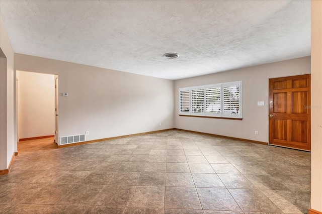 empty room featuring a textured ceiling, baseboards, and visible vents