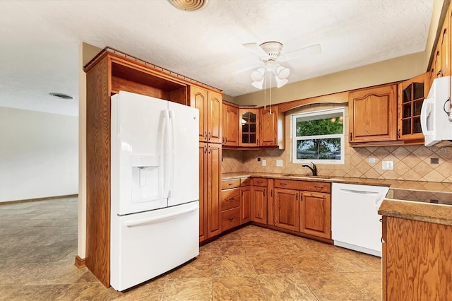 kitchen featuring brown cabinets, backsplash, a ceiling fan, and white appliances