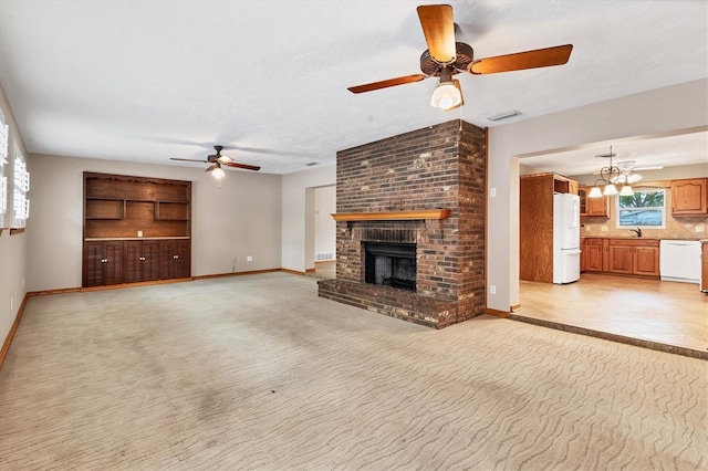 unfurnished living room with baseboards, a brick fireplace, visible vents, ceiling fan with notable chandelier, and light colored carpet