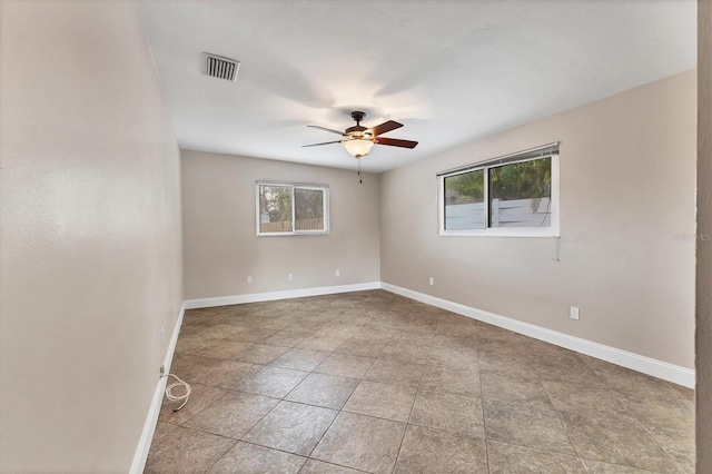 empty room with visible vents, baseboards, a ceiling fan, and a healthy amount of sunlight