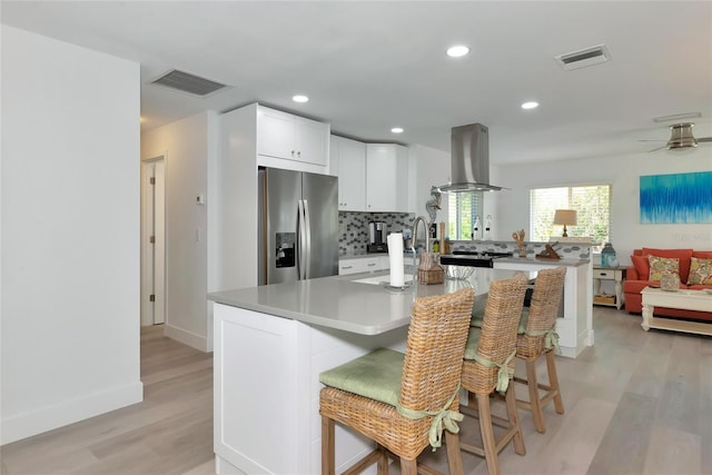 8152 Seashell St, Englewood, FL 34224 - kitchen featuring island exhaust hood, stainless steel refrigerator with ice dispenser, light wood-style flooring, white cabinets, and open floor plan