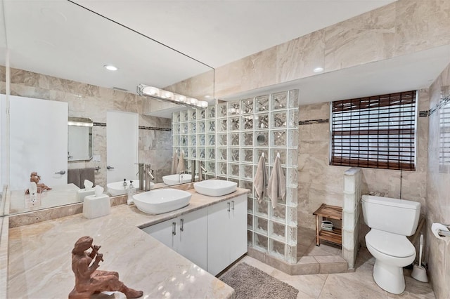 full bathroom with a sink, tile walls, and toilet