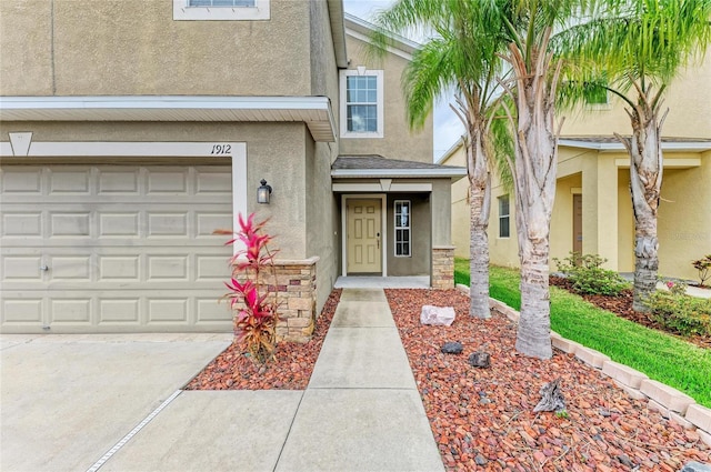 1912 Hawks View Dr, Ruskin, FL 33570 - property entrance featuring an attached garage, stone siding, driveway, and stucco siding