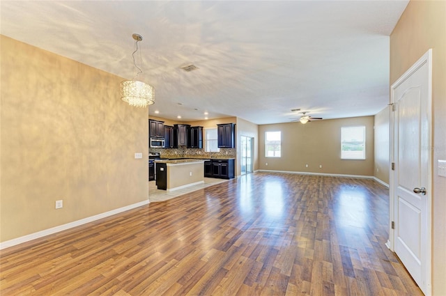 1912 Hawks View Dr, Ruskin, FL 33570 - unfurnished living room featuring visible vents, baseboards, light wood-type flooring, and ceiling fan with notable chandelier