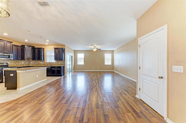 1912 Hawks View Dr, Ruskin, FL 33570 - kitchen featuring light wood-type flooring, open floor plan, a center island, decorative backsplash, and appliances with stainless steel finishes