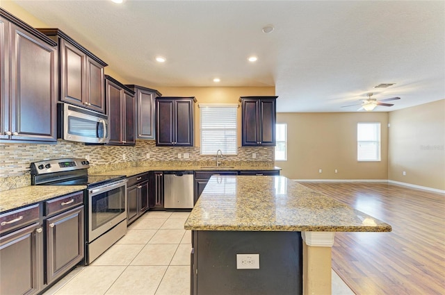 1912 Hawks View Dr, Ruskin, FL 33570 - kitchen featuring tasteful backsplash, open floor plan, a kitchen island, stainless steel appliances, and a sink