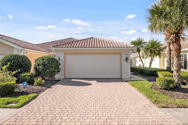 view of front of house featuring a garage, driveway, stucco siding, and a tiled roof