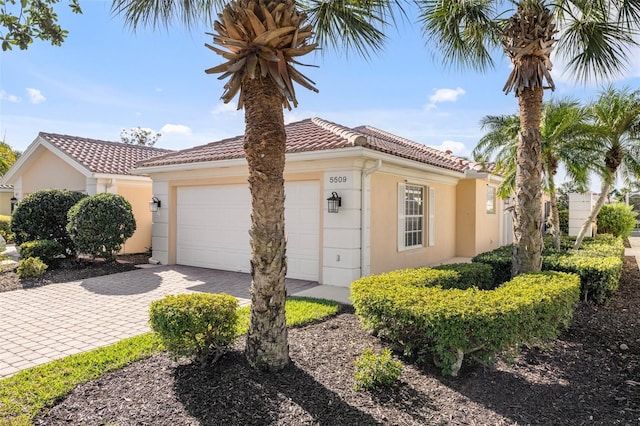 mediterranean / spanish house with a tiled roof, an attached garage, driveway, and stucco siding