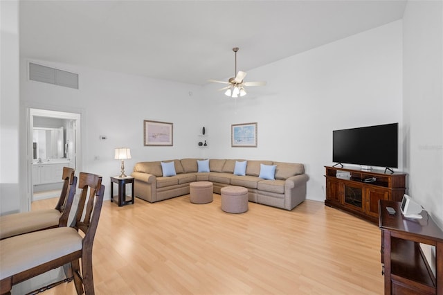 living room featuring visible vents, light wood finished floors, and a ceiling fan