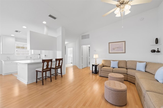 living area with light wood-style floors, a ceiling fan, and visible vents