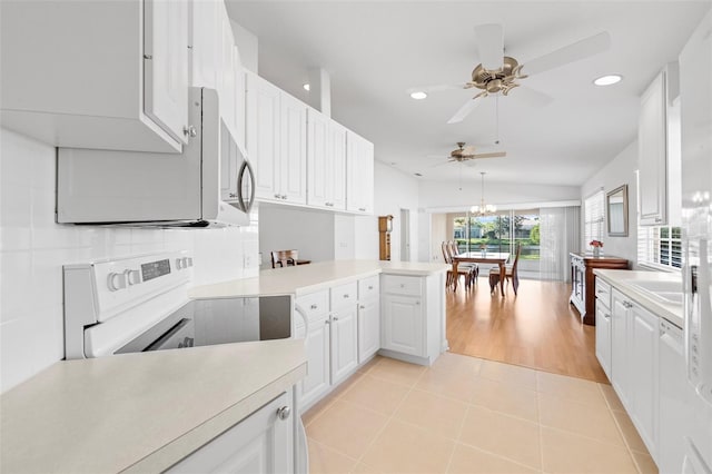kitchen with light tile patterned floors, light countertops, a peninsula, electric stove, and ceiling fan with notable chandelier