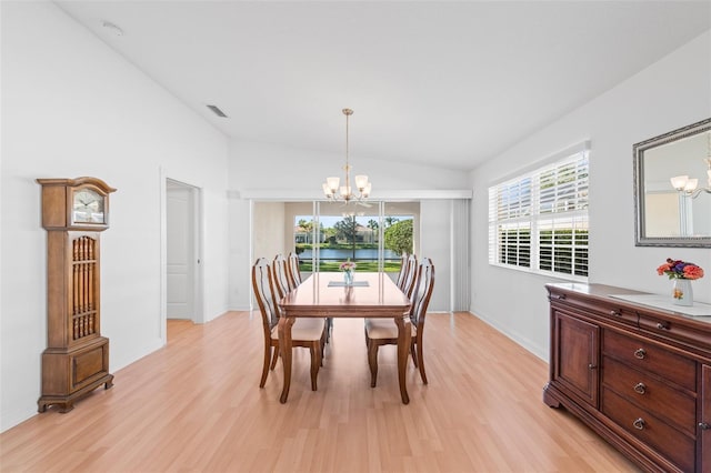 dining space featuring visible vents, baseboards, a chandelier, light wood-style floors, and vaulted ceiling