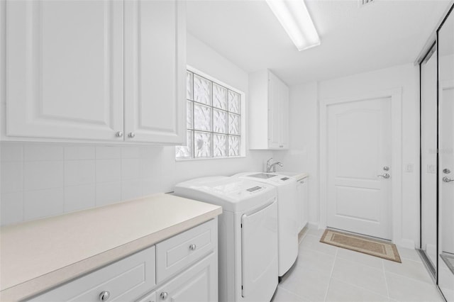 clothes washing area with washer and dryer, light tile patterned floors, and cabinet space
