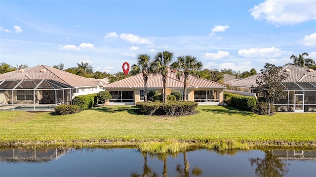 rear view of house with a water view, a tile roof, a yard, and stucco siding