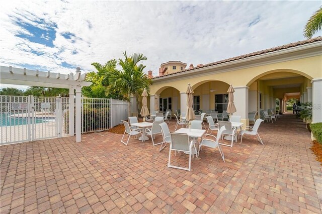 view of patio with outdoor dining area, a community pool, and fence