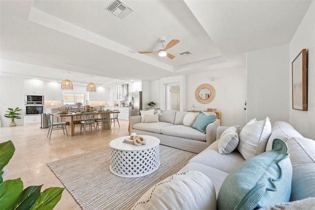 living room featuring visible vents, ceiling fan, a tray ceiling, and light tile patterned flooring